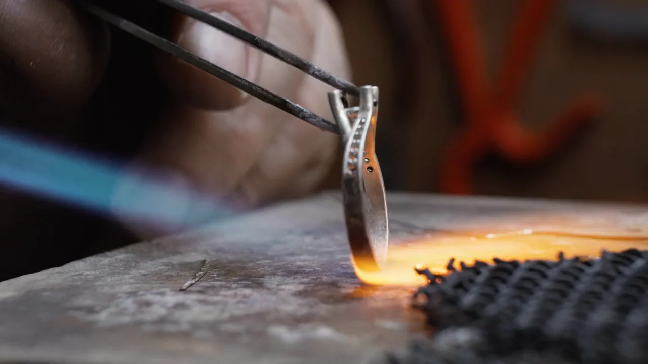 A ring held in tongs over a jeweller’s torch at the bench